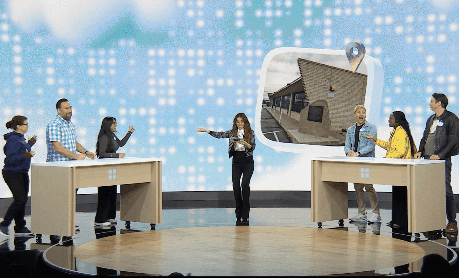Host, Brenda Song, leading a fun trivia game with two teams on stage at a Microsoft event, featuring a nostalgic image on screen.